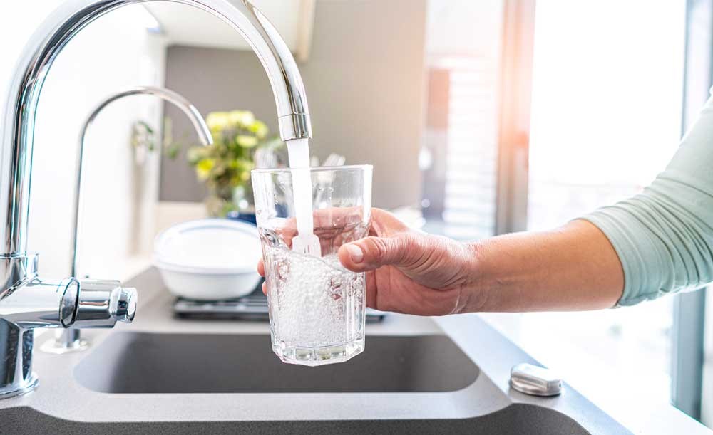 Person filling a water glass from the sink